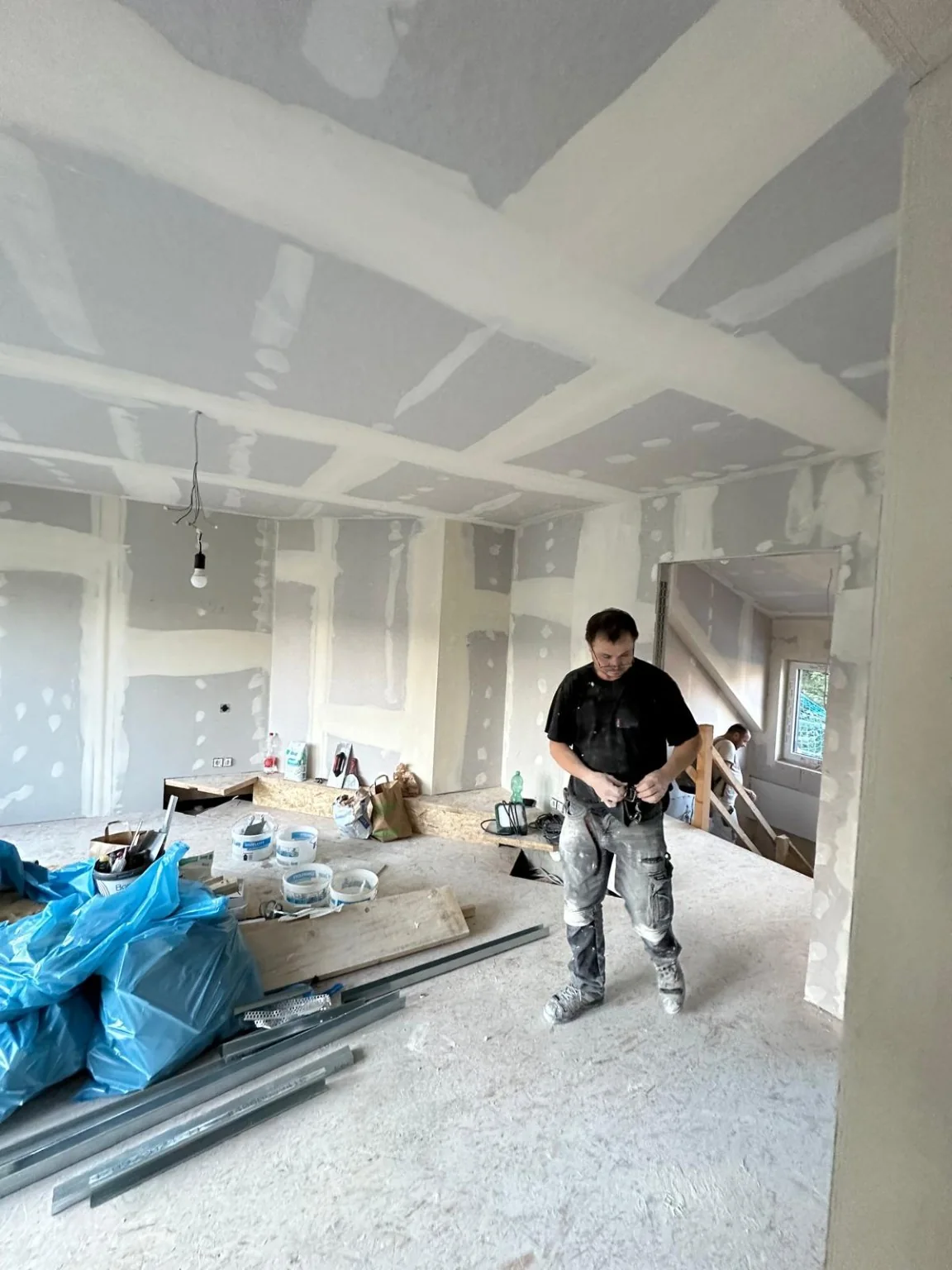 Ausbauarbeiten im Dachgeschoss mit verspachtelten Wand- und Deckenfugen und einer Person im Vordergrund