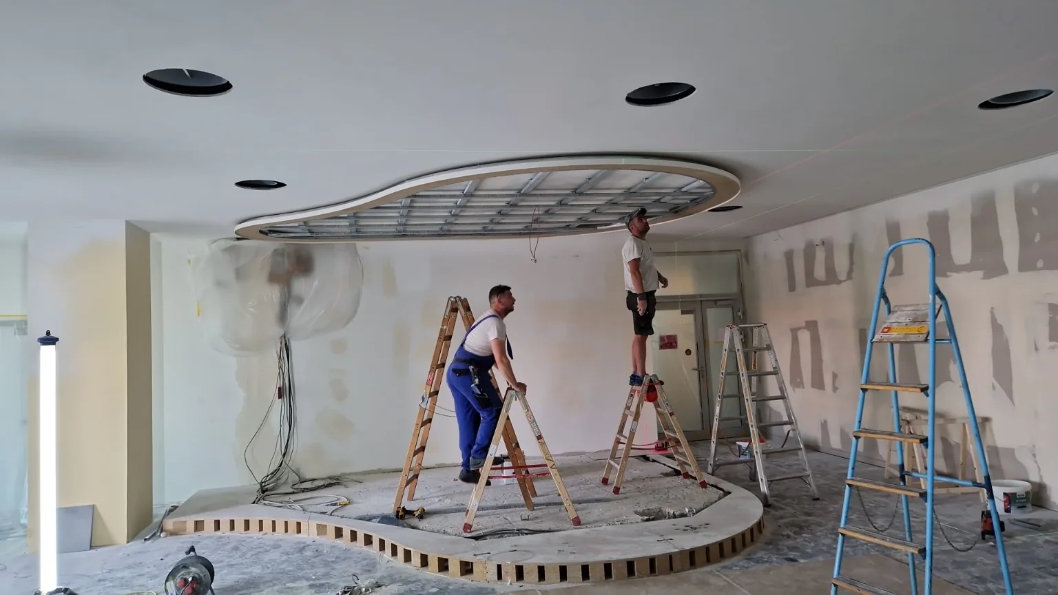 Handwerker während der Montage der Unterkonstruktion einer geschwungenen Deckenform