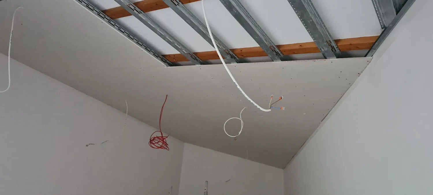 Teilweise beplankte Decke mit noch sichtbaren Metallprofilen und Kabeln